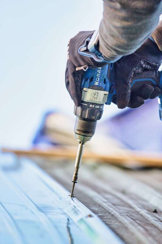 Metal roof installer drilling holes for metal roofing